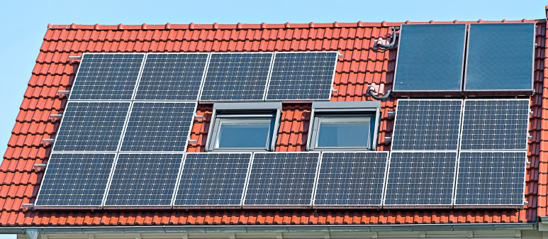Auch kombinierbar: Solarthermie- und Photovoltaikzellen auf einem Dach. Foto: Anspach, dpa