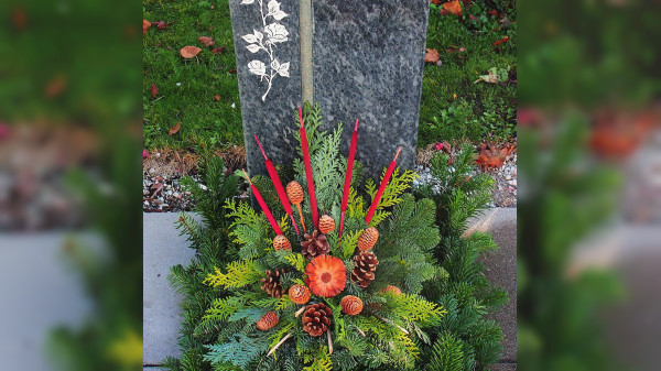 Blumen und Gestecke schmücken Gräber zu Ehren der Toten