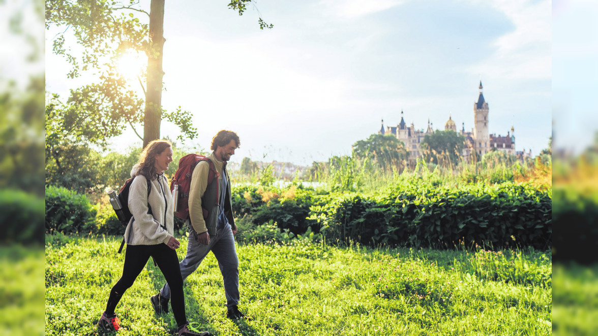 Wanderer auf dem Naturparkweg mit Blick auf das Schweriner Schloss. Foto: TVM/Gaensicke